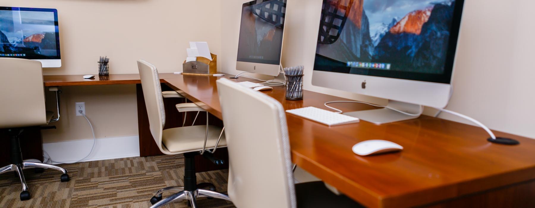 a desk with a computer and chairs